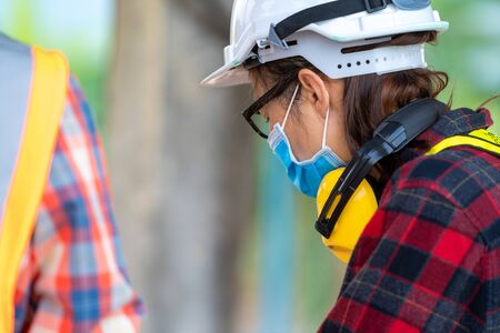 Builders wearing safety helmet with blueprint at construction,Concept of residential building under...
