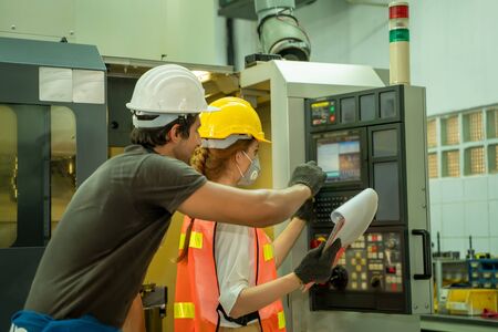 Businessmen or male engineers and female engineers with hygienic mask are working on the machine at...