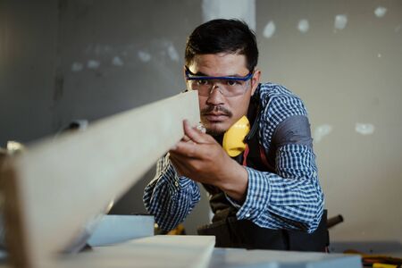 Carpenter working on woodworking machines in carpentry shop,Man doing woodwork in carpentry.の写真素材