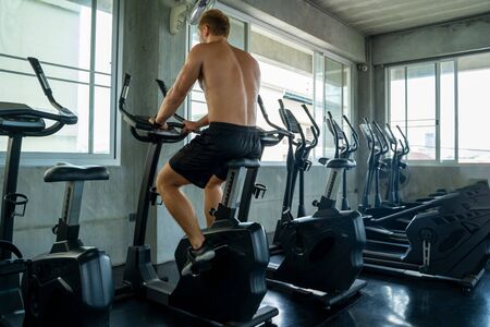Man spinning an electric bicycle in the gym For good health and allowing the muscles to relax,Men workout activity concept.の写真素材