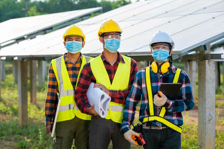 Solar power plant,Electrician wearing a medicine healthcare mask working and checking solar plant at...