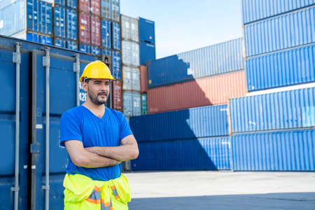 Portrait of container worker leaning on cargo container and looking up.