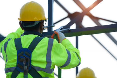 Construction workers wearing safety harness belt working at high place at building site.