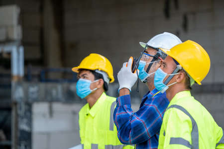 Engineer group wearing protective mask to Protect Against Covid-19 use radio communications to...