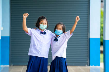 Elementary school students with face mask back at school after covid-19 quarantine and lockdown,Greeting.の写真素材