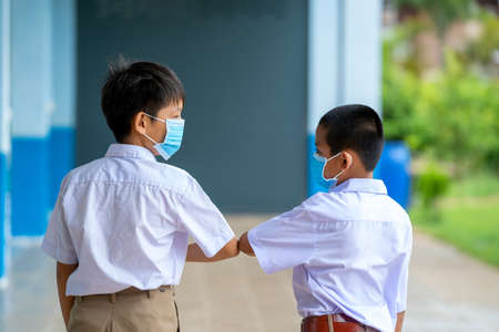Elementary school students with face mask back at school after covid-19 quarantine and lockdown,Greeting.の写真素材