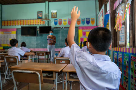 Asian student with hands up during learning in classroom at elementary school.の写真素材