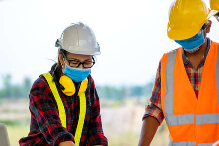Architects discuss with engineer about construction project at construction site.の写真素材