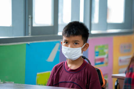 Portrait of an elementary school wearing protective mask to Protect Against Covid-19  listening to...