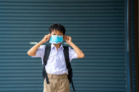 School kids wearing medical mask or surgical mask to protect her from virus are standing at...