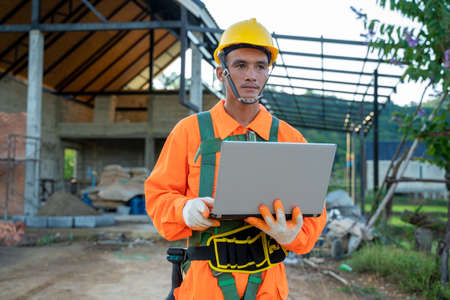 Engineer working with laptop on architectural project at construction site.の写真素材