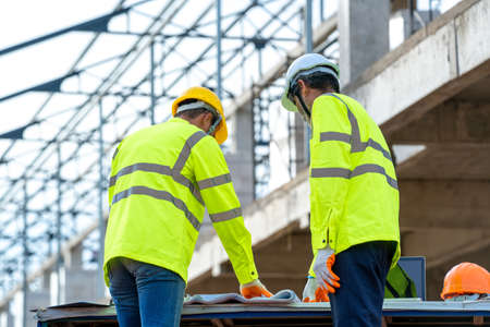 Engineers discussion with architect about detail of building at construction site.