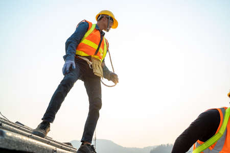 Construction worker with nail gun installing new roof in the building under construction.の写真素材