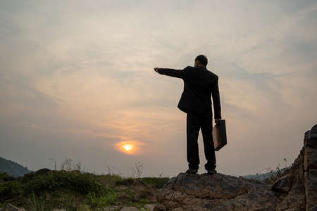 Businessman standing on mountain at sunset background,Business success concept.の写真素材