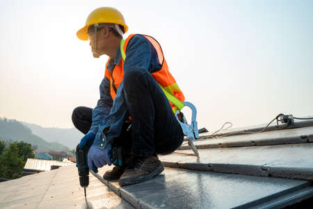 Construction worker with nail gun installing new roof in the building under construction.の写真素材