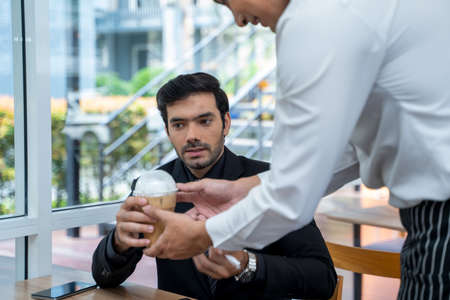 Professional Barista serving coffee and communicating with businessman in coffee shop.の写真素材