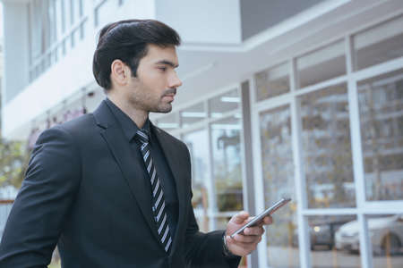 Handsome businessman talking on mobile phone outside the building office.の写真素材