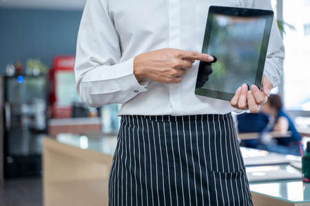 Asia barista using tablet take order from customer in coffee shop,Food and drink business concept.の写真素材