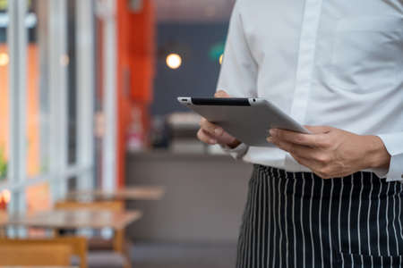 Employees use tablets and take orders in a coffee shop.