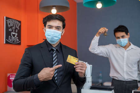 Portrait of businessman showing a credit card in coffee shop.の写真素材