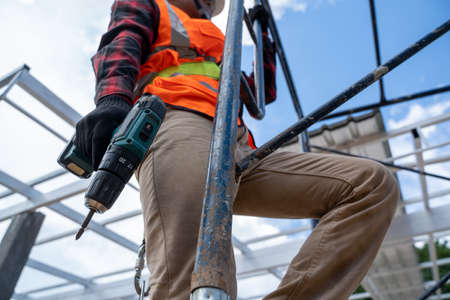 Construction workers wearing safety harness working at high level in the construction site,Roofing...