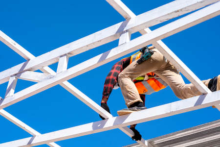 Roofer worker in protective uniform wear installing metal roof on top of the new roof,Concept of residential building under construction,Working on height.の写真素材
