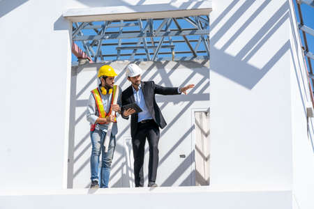 Architects discuss with head engineer about construction project on workplace at construction site.の写真素材