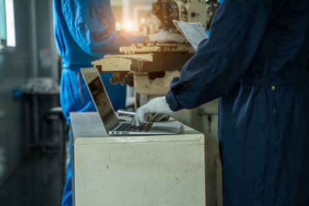 Industrial workers with a laptop working on the background of the equipment at metal industrial manufacturing factory.の写真素材