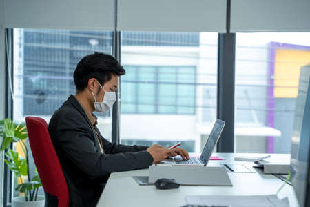 Business people wearing protective face mask while working together during coronavirus epidemic in office.の写真素材