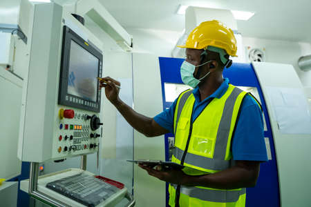 Factory worker wearing protective mask to Protect Against Covid-19 are working and checking machine...