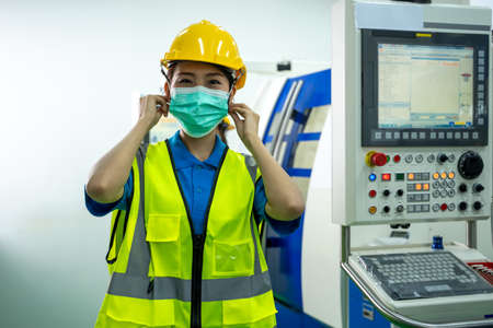 Industrial worker wearing protective mask to Protect Against Covid-19 standing in industrial factory.の写真素材