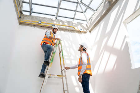 Engineer technician watching team of workers on high steel platform at construction site,Engineer...