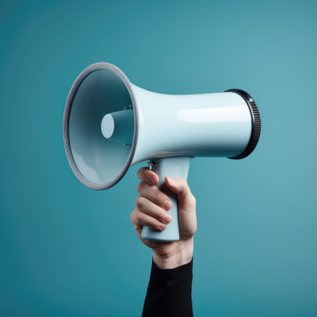 Hand is hold megaphone, Hand with mouthpiece on empty blue background.の素材