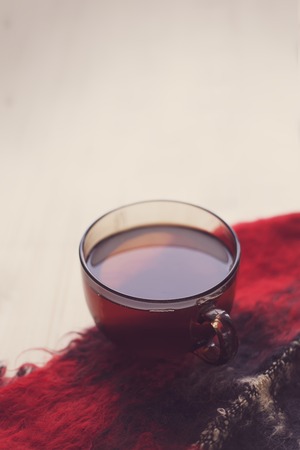 A Cup of hot tea is on the warm scarf on the background of wooden boards, comfort, rest, relaxation, holidays, vacation, tonedの写真素材