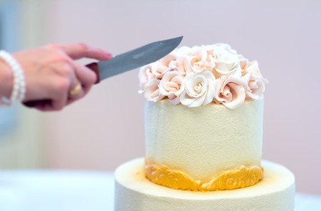 Festive wedding cake with flowers, yellow-orange flowers, bunk, beautiful, gentle, the bride cuts the cake.の写真素材
