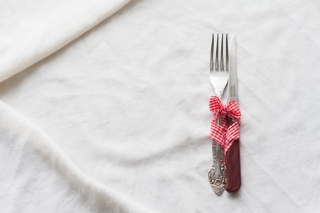 The table setting fork knife bound with red ribbon, a symbol of love, holiday, relationship.の写真素材