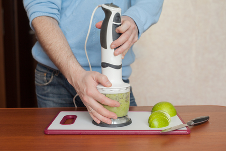 man prepares in a blender dessert, smoothies, apples and berriesの写真素材