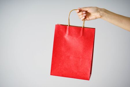 Paper red craft bag, eco packaging in a female hand, on a gray background.の写真素材
