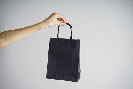 Paper blue craft bag, eco packaging in a female hand, on a gray background.の写真素材