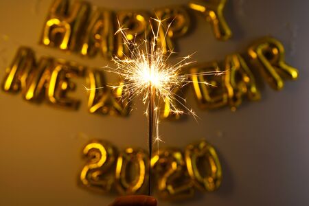 Celebrating New Year 2020, golden foil balloons 2020 on gray background with sparklersの写真素材