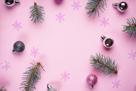 Christmas composition. Christmas decorations pink balls and snowflakes with Christmas tree branches on a pink background. Flat lay, top view, place for text.の写真素材