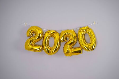 Celebrating the New Year 2020. Gold foil balloons 2020 on a gray background. Foil balls, festive concept for winter holidays.の写真素材