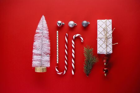 Christmas concept. Christmas gift, sweets, pine branch, toys on a red background. Flat lay.の写真素材