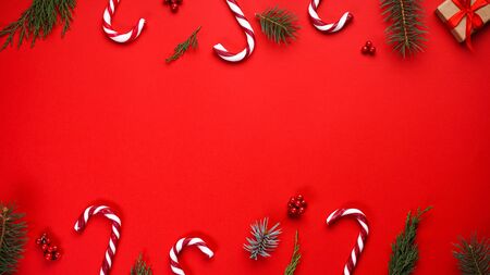 Christmas composition with candies and Christmas decoration on a red background, place for text. Flat lay.の写真素材