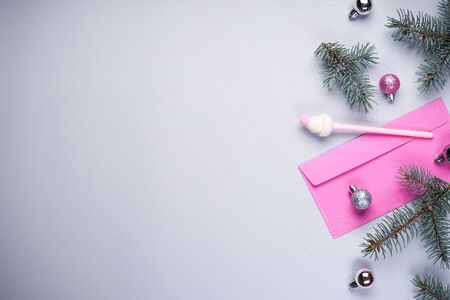 A branch of blue pine, pink envelope, pink pen, Christmas balls on a gray background.
Place for text, flat lay.の写真素材