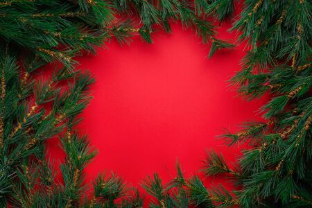 Christmas or New Year decorations background: Christmas tree branches on a red background with space for textの写真素材