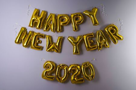 Celebrating the New Year 2020. Gold foil balloons on a gray background. Foil balls, festive concept for winter holidays.の写真素材