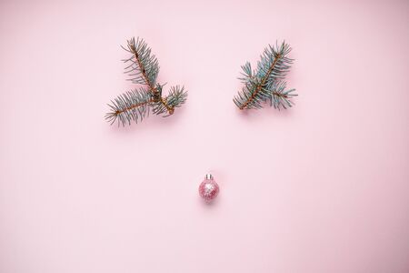 Deer made of Christmas decorations and pine branches, on a pastel pink background.の写真素材