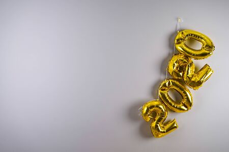 Celebrating the New Year 2020. Gold foil balloons 2020 on a gray background. Foil balls, festive concept for winter holidays.の写真素材