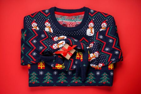 Christmas sweater with a pattern on a red background with a gift, top viewの写真素材